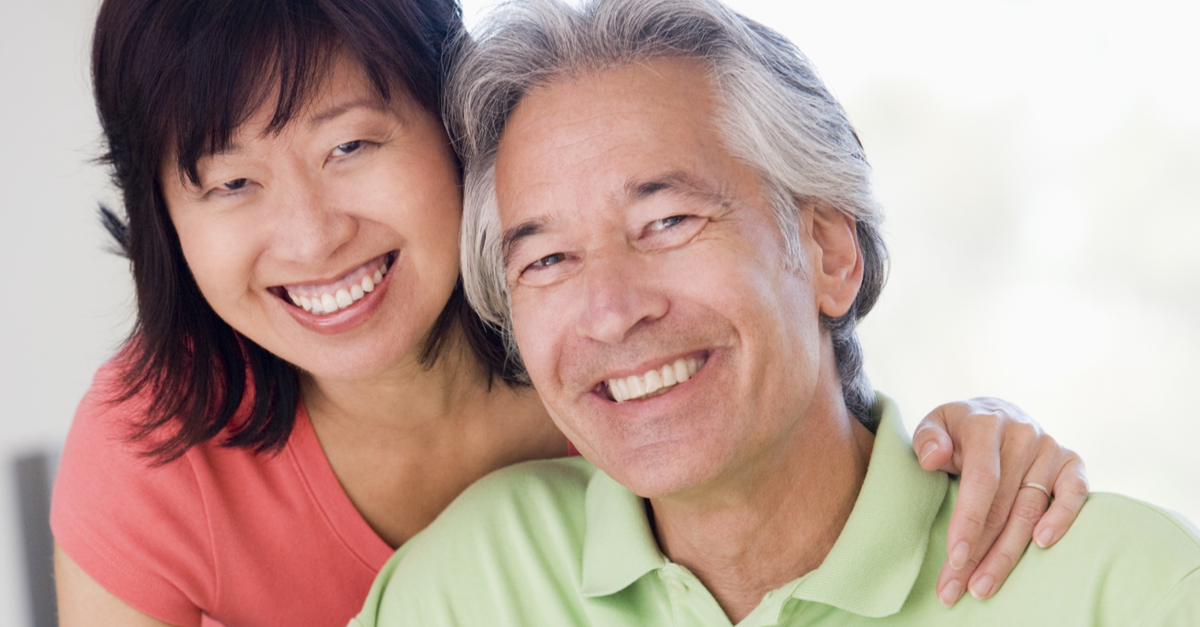 Chinese Malaysian husband and wife couple smiling at the camera in close embrace
